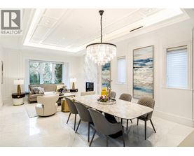 A dining room with a large table and chairs.