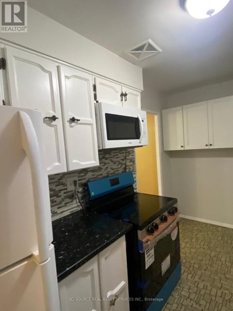 A kitchen with white cabinets and a black counter top.
