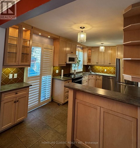 A kitchen with wooden cabinets and a stainless steel refrigerator.