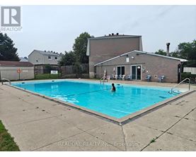 A person is swimming in a pool with a house in the background.