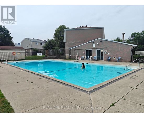 A person is swimming in a pool with a house in the background.