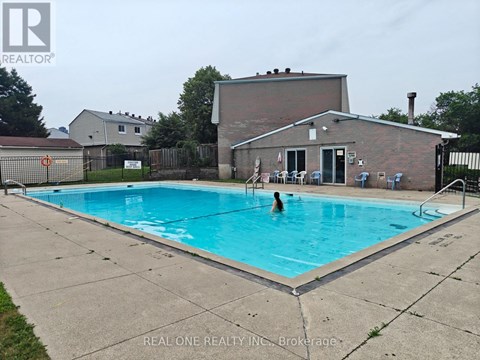 A person is swimming in a pool with a house in the background.