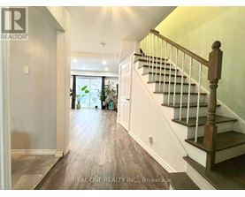 A hallway with a staircase and a door leading to a balcony.