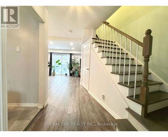 A hallway with a staircase and a door leading to a balcony.