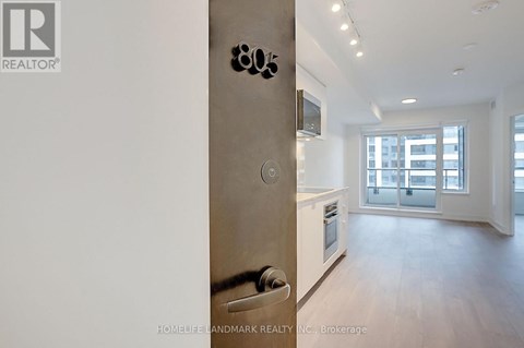 A modern kitchen with a stainless steel refrigerator and wooden flooring.