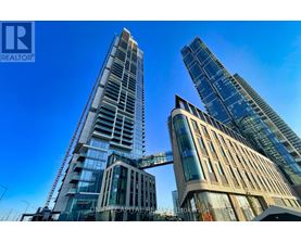 A tall building with a glass facade stands next to a shorter building with a curved facade.