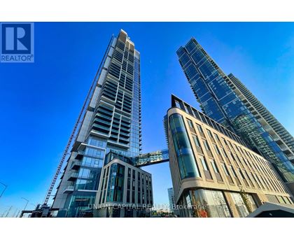 A tall building with a glass facade stands next to a shorter building with a curved facade.
