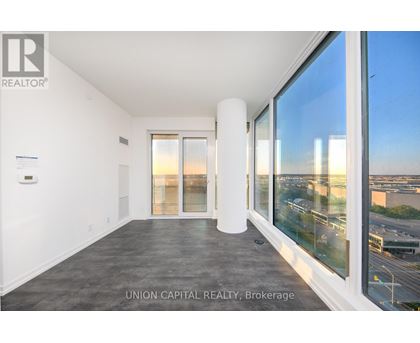 A spacious room with a view of the cityscape through large windows.