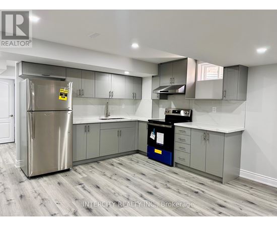A kitchen with a stainless steel refrigerator and wooden flooring.