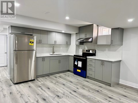 A kitchen with a stainless steel refrigerator and wooden flooring.