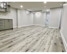 A spacious room with wood flooring and white walls.