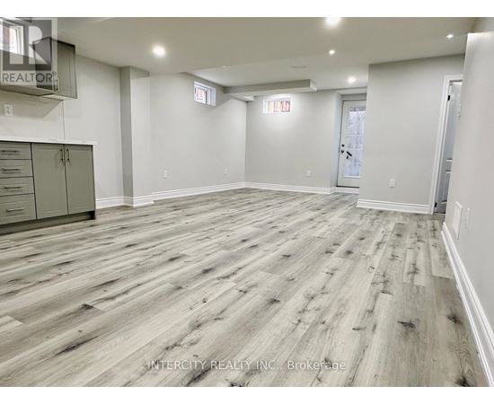 A spacious room with wood flooring and white walls.