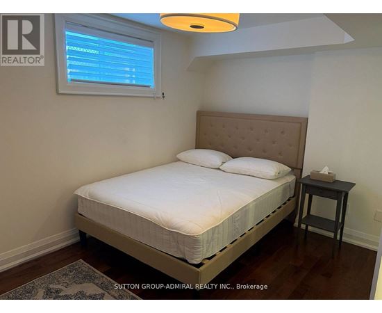 A bedroom with a bed, nightstand, and window.