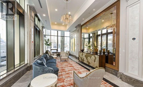 A well-lit, modern living room with a grey sofa and a chandelier.