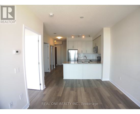 A spacious kitchen with white cabinets and a wooden floor.
