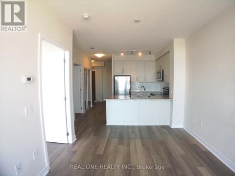 A spacious kitchen with white cabinets and a wooden floor.