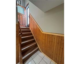 A wooden staircase with a white tiled floor.