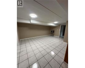 A spacious room with a white tile floor and a small refrigerator.