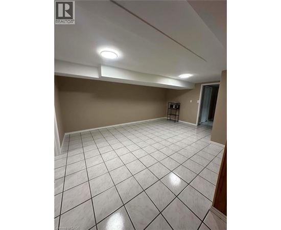 A spacious room with a white tile floor and a small refrigerator.