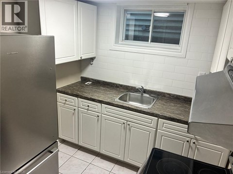 A kitchen with white cabinets and a stainless steel refrigerator.