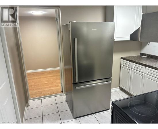A kitchen with a refrigerator and a stove top oven.