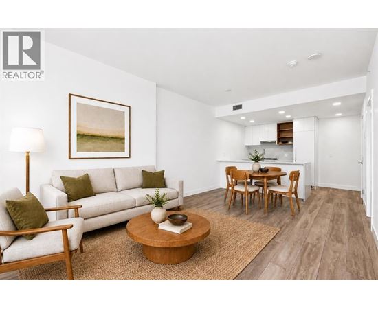 A living room with a white couch, a coffee table, and a painting on the wall.