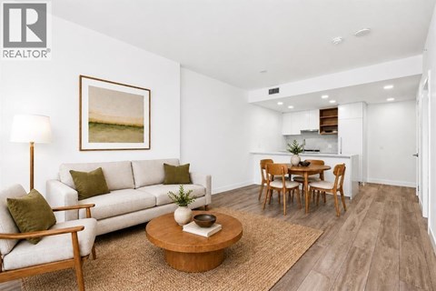 A living room with a white couch, a coffee table, and a painting on the wall.