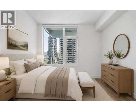 A bedroom with a large bed, a bench, and a window overlooking a cityscape.