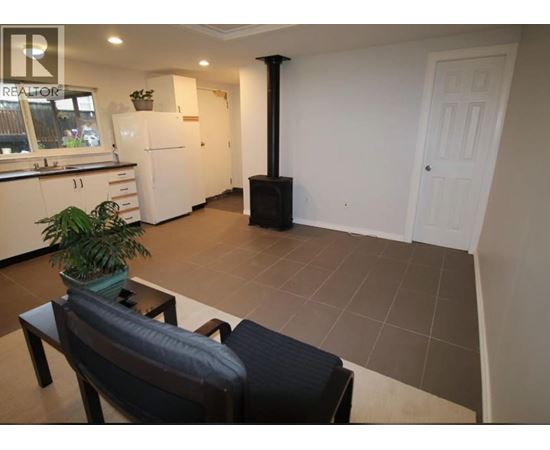 A living room with a black couch and a plant on a table.