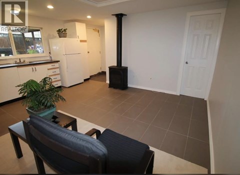 A living room with a black couch and a plant on a table.