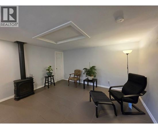 A living room with a wood stove and a black chair.