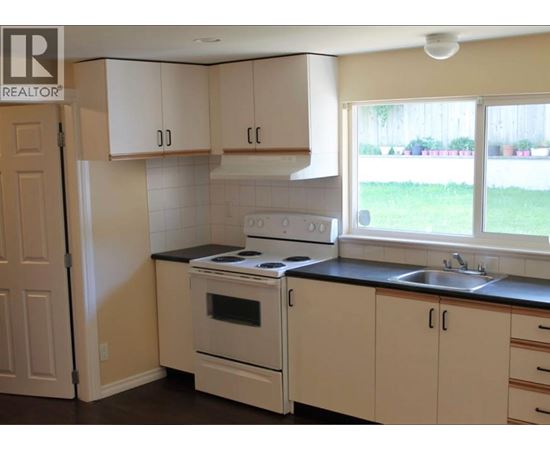 A kitchen with white cabinets and a black countertop.