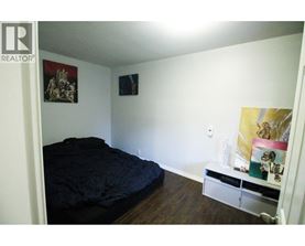 A bedroom with a bed, a shelf, and pictures on the wall.