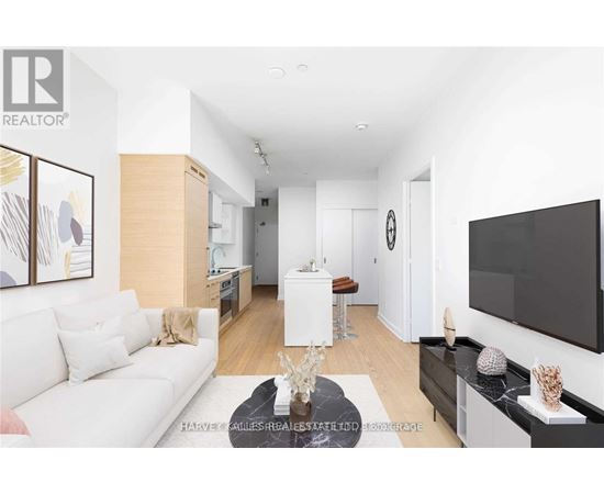 A living room with a white couch and a flat screen TV mounted on the wall.