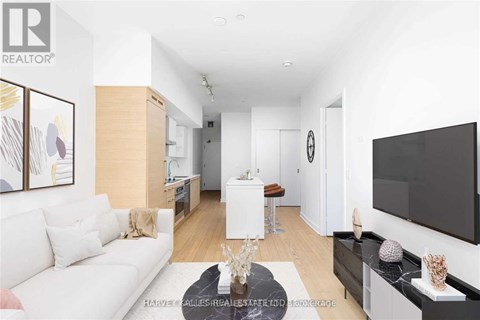 A living room with a white couch and a flat screen TV mounted on the wall.