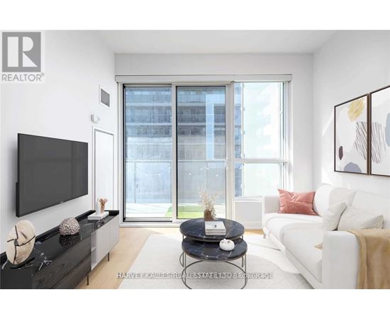 A living room with a flat screen TV, a black coffee table, a white couch, and a large window with a view of a building outside.