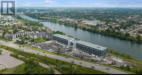 An aerial view of a large building complex with a body of water in the background and the text "FRITTON CAPITAL INC. Brokerage" visible.