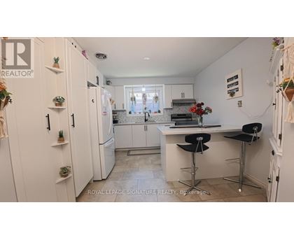 A kitchen with white cabinets and a bar area with stools.