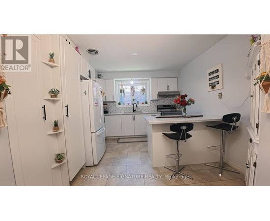 A kitchen with white cabinets and a bar area with stools.