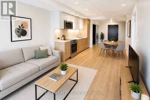 A modern living room with a grey sofa, wooden coffee table, and a dining area with a grey table and chairs.