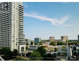 A view of a cityscape with a tall building in the foreground and other buildings in the background.