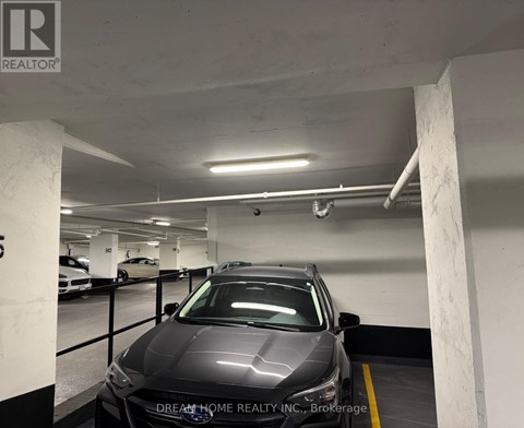 A car is parked in a garage with the logo of Dream Home Realty Inc. on the wall.