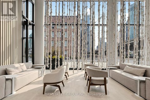 A modern living room with white furniture and a large window with a view of the city.