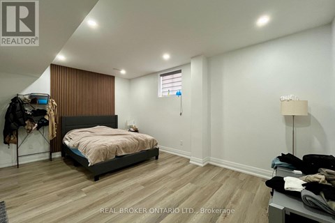 A bedroom with a bed, a clothing rack, and a lamp.