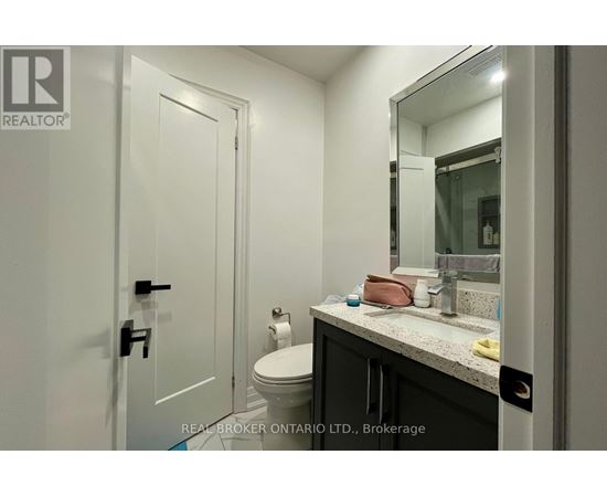 A bathroom with a toilet, sink, and mirror.