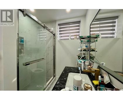 A bathroom with a glass shower door and a sink with a mirror above it.