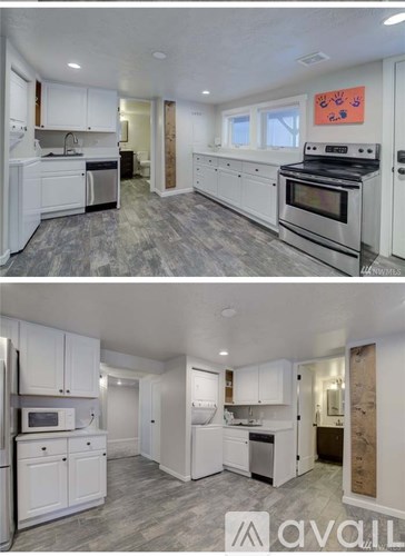 A kitchen with white cabinets and a grey floor.