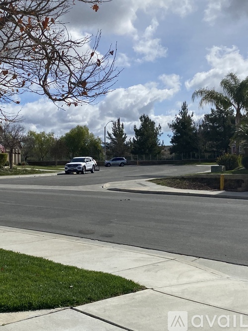 A car is driving on a street with trees and houses in the background.