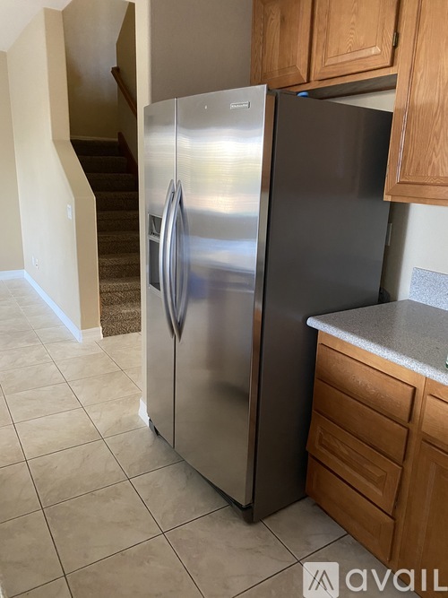 A stainless steel refrigerator in a kitchen with wooden cabinets.