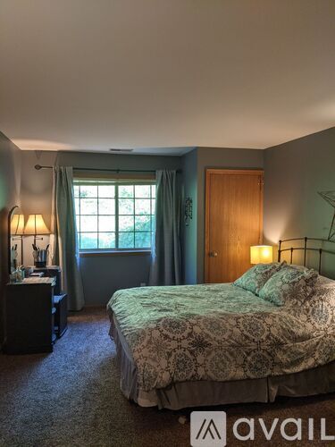 A bedroom with a bed, nightstand, and window.
